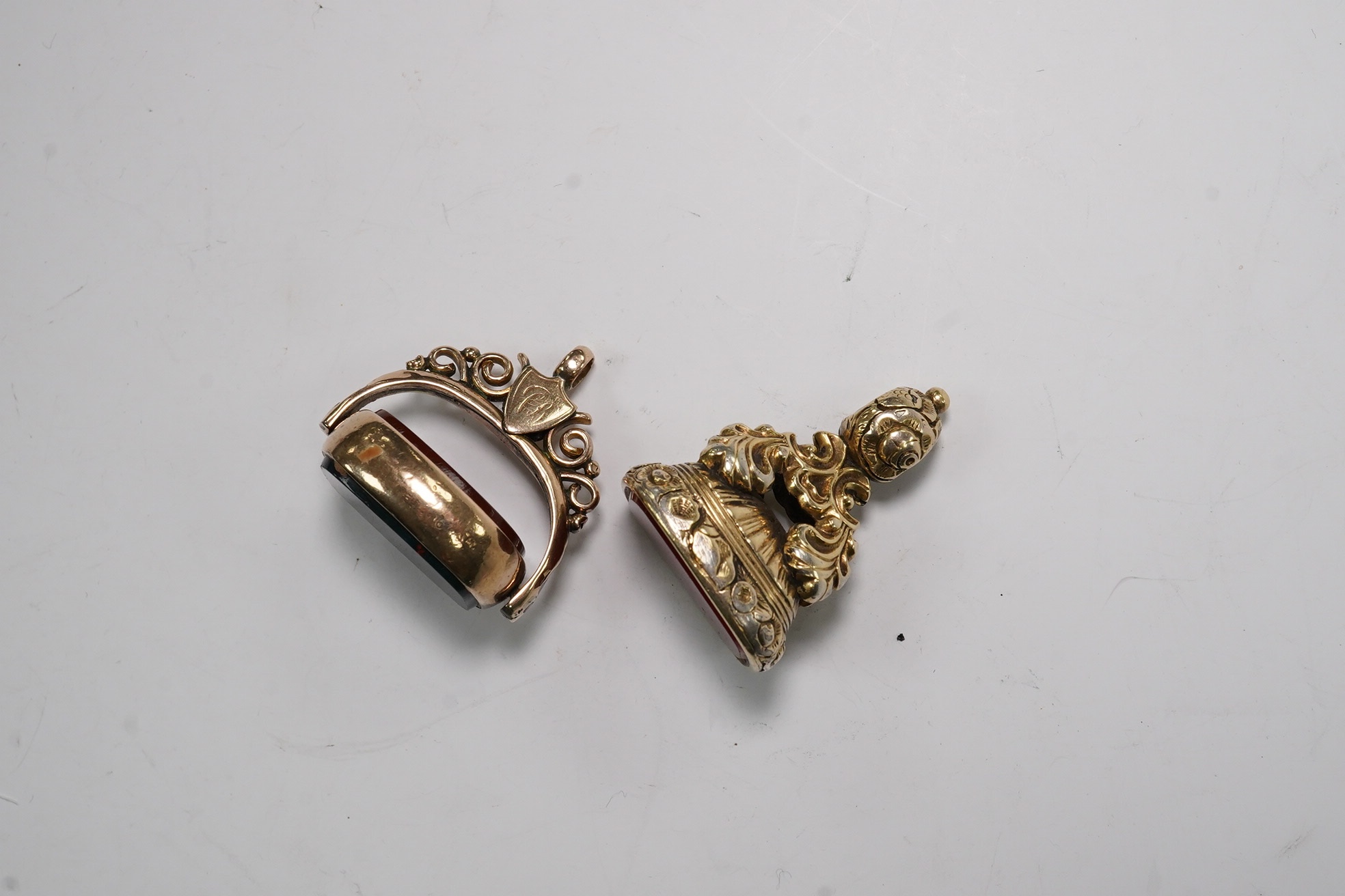 An early 20th century gold, carnelian and bloodstone set spinning fob, 34mm and one other gilt metal and carnelian set fob. Condition - poor to fair